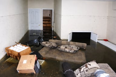 Flooded interior space with furniture and debris.