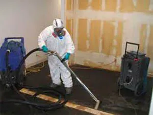 Worker vacuuming a floor in a safety suit.