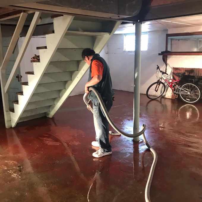 Person cleaning basement with a vacuum hose